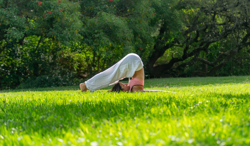 Young Woman on Plow Pose Practicing Yoga in a Green Park.Wellness Concept
